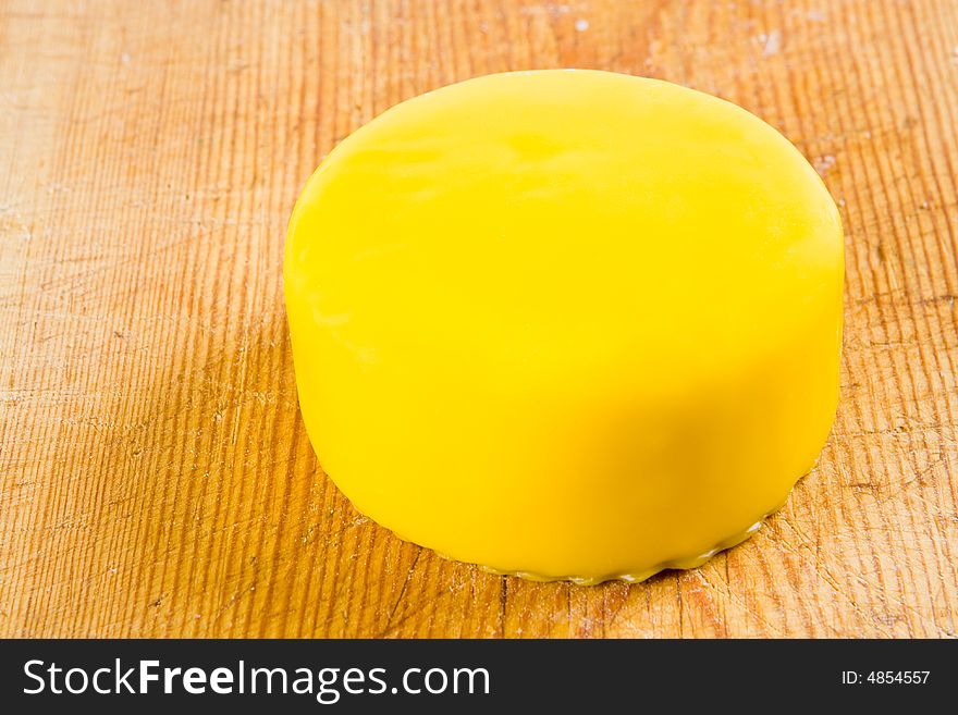 Cheese in yellow wax on a wooden board
