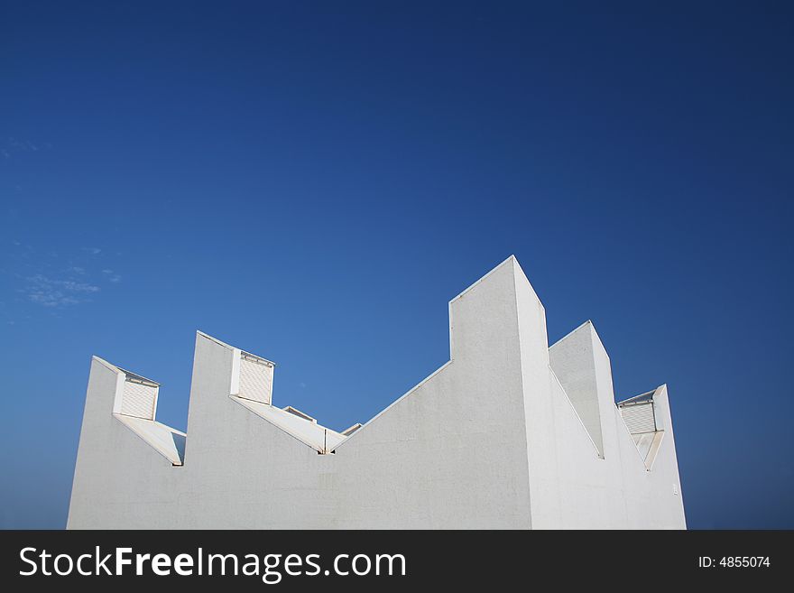 An isolated rare white building top with a clean blue background. An isolated rare white building top with a clean blue background