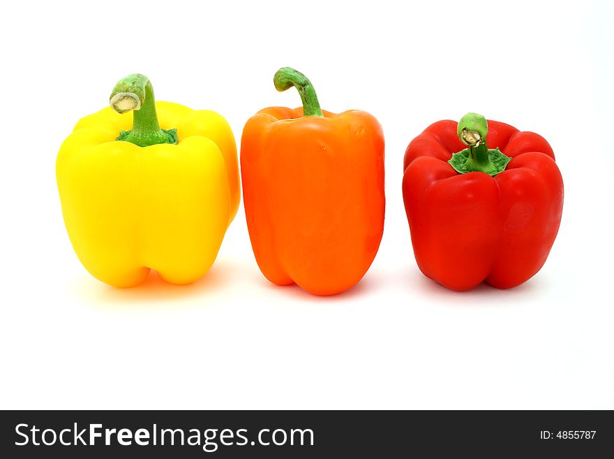Fresh orange, yellow and red  peppers over a white surface