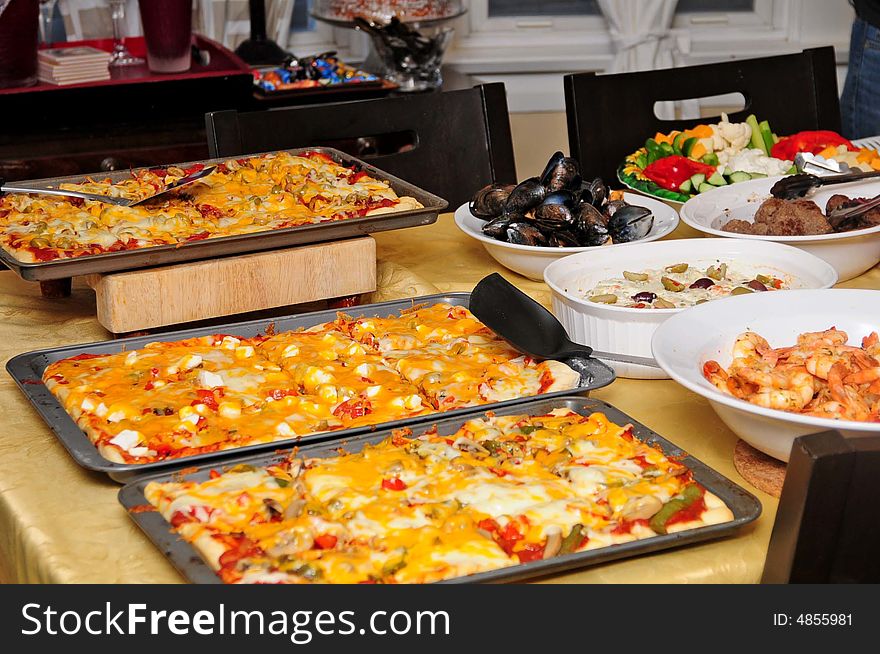 A full table with salad, shrimp, veggies and pizza. A full table with salad, shrimp, veggies and pizza