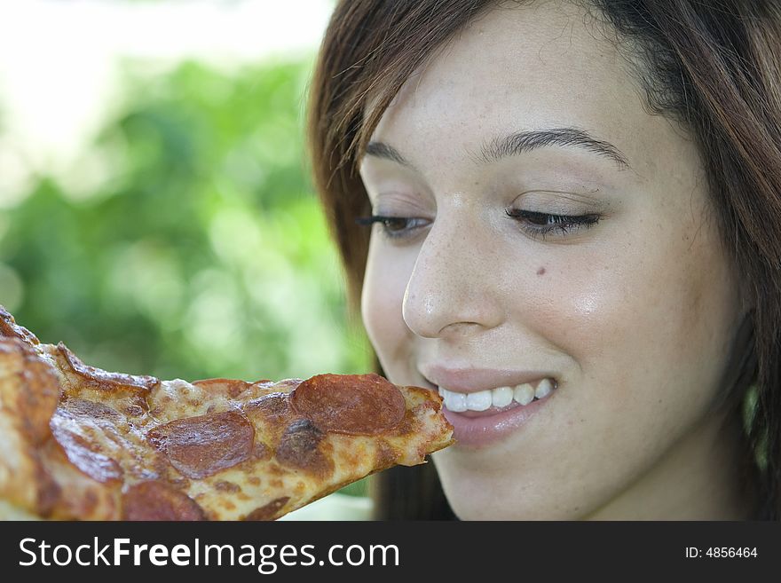 Sweet and attractive girl eating pizza slice