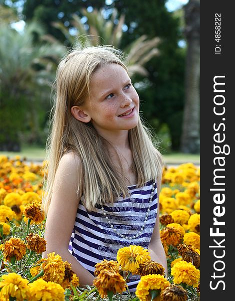A white caucasian girl child sitting amongst yellow flowers. A white caucasian girl child sitting amongst yellow flowers