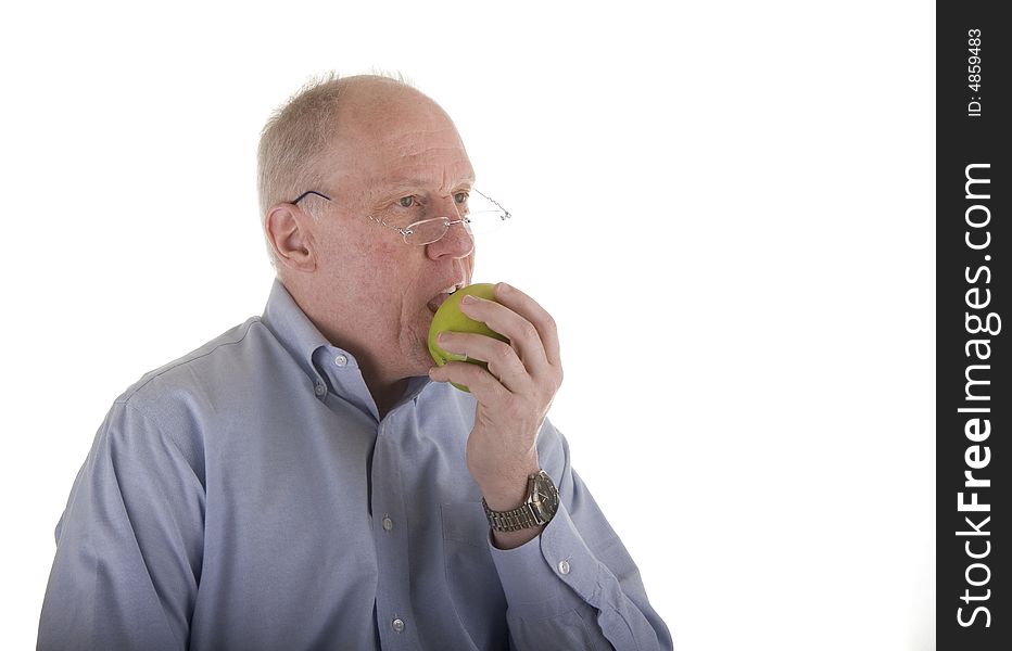 An older man enjoying a healthy snack of a green apple. An older man enjoying a healthy snack of a green apple