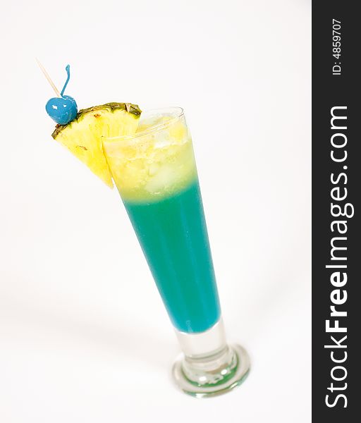 Green cocktail with pineapple and blue cherry
