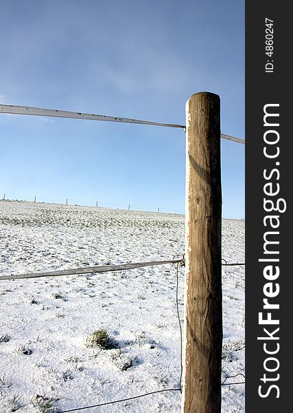 A post and a segment of fence on a meadow in winter. A post and a segment of fence on a meadow in winter