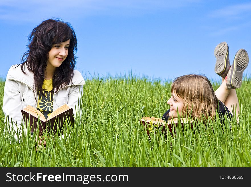 Couple of friends enjoying a book in a meadow