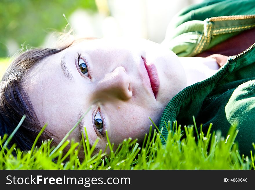 Young woman staring at camera in the grass. Young woman staring at camera in the grass.