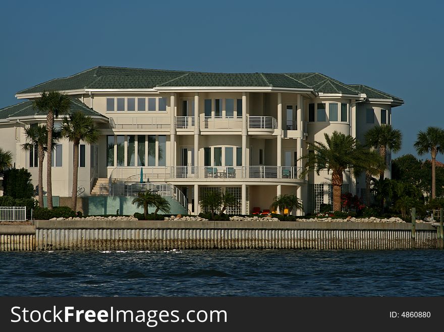 Expensive waterside mansion surrounded with palm trees