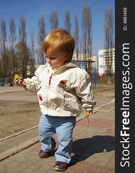 Little beautiful girl play whith yellow flowers