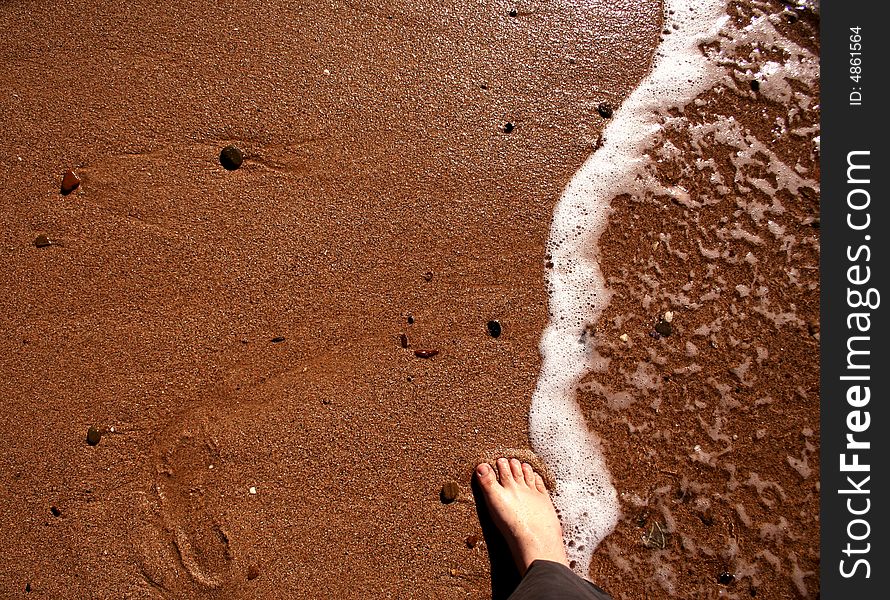 A foot and an empty foot track on a beach. A foot and an empty foot track on a beach.