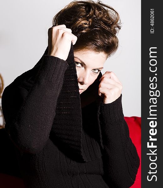 Beautiful woman wearing a black sweater pulling her collar around her face