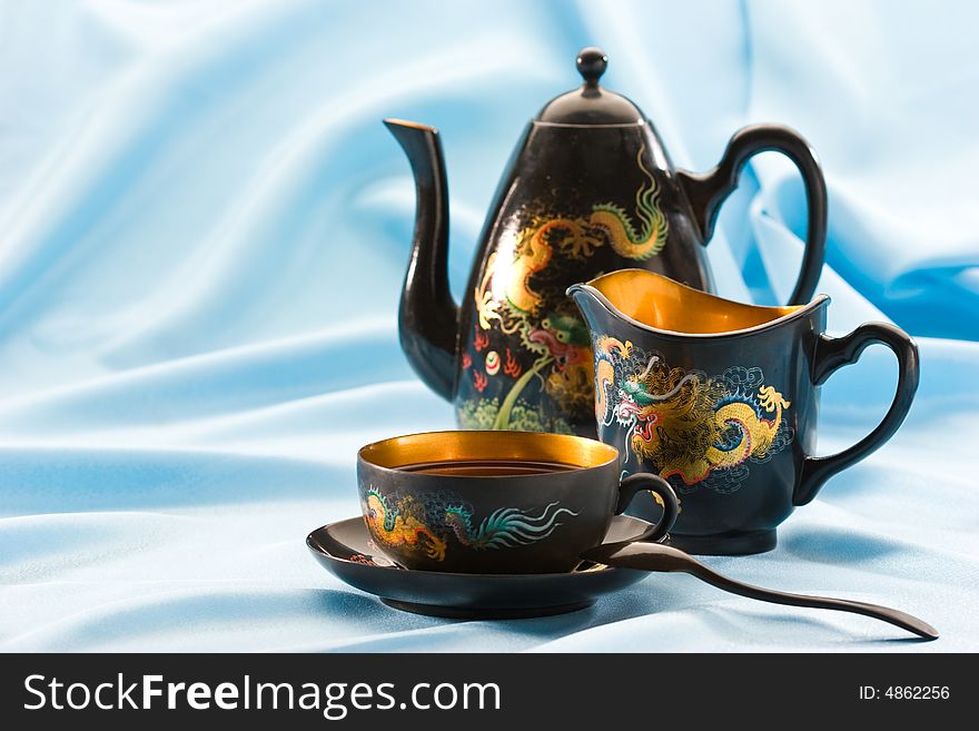 Teapot and cup filled with black tea. Teapot and cup filled with black tea