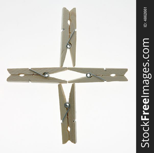 Four isolated wooden clothespins in a cross. Four isolated wooden clothespins in a cross