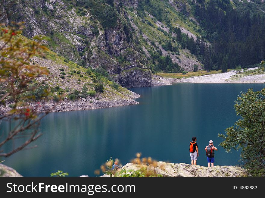 Trekkers watching a blue mountain lake in summer. Trekkers watching a blue mountain lake in summer