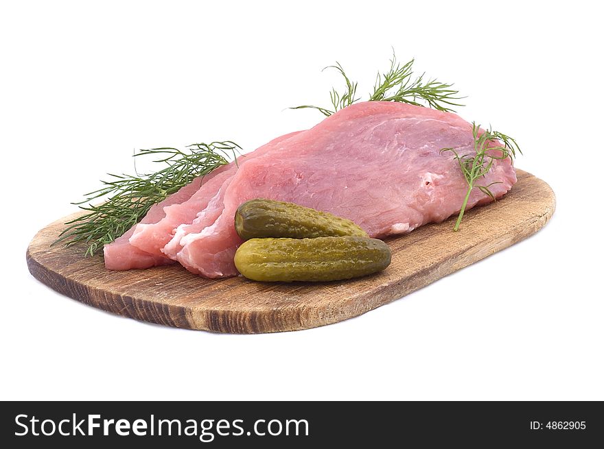 Raw pork schnitzel with pickled cucumbers and dill on a wooden hardboard isolated on white