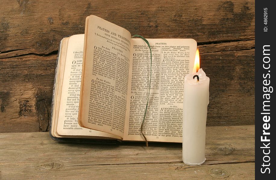 Old prayer book and candle agapnst a background of rustic wood