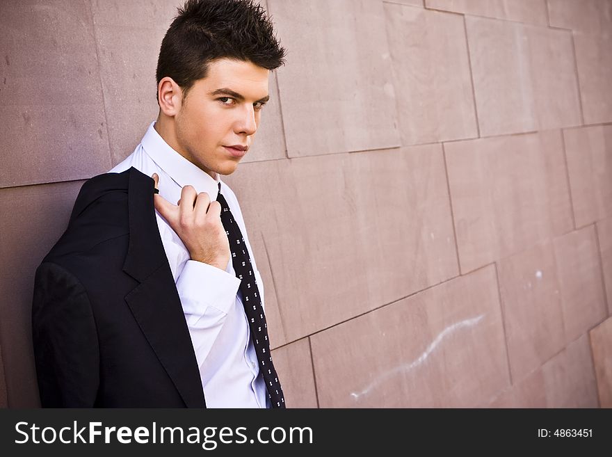 Lone businessman posing on wall. Lone businessman posing on wall