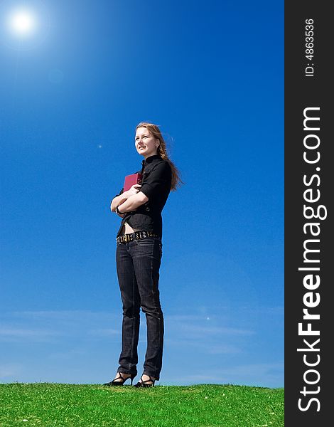 The young attractive student with the book on a background of the blue sky