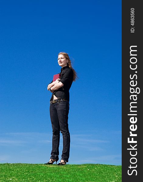 The young attractive student with the book on a background of the blue sky