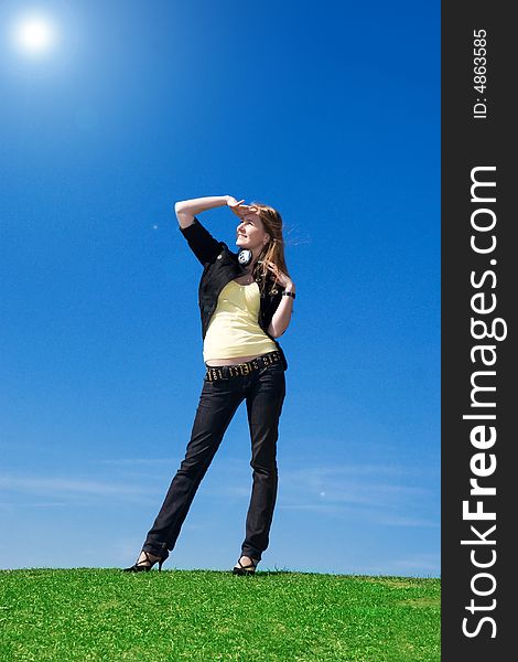 The young attractive girl with headphones on a background of the blue sky