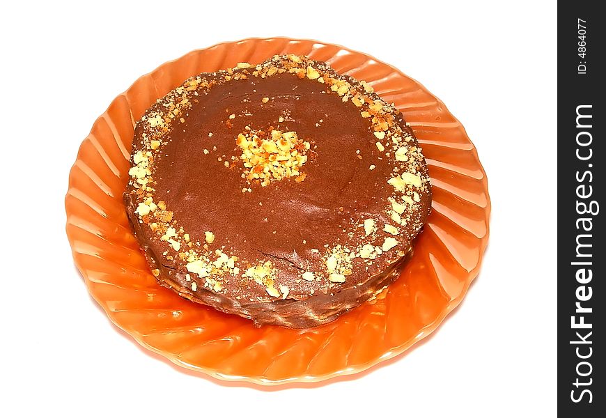 Home made round chocolate cake on the orange plate. It's made of sweet wafers smeared with cacao cream. 
Top is covered by chocolate icing with walnut's pieces and waffle crumbs. Home made round chocolate cake on the orange plate. It's made of sweet wafers smeared with cacao cream. 
Top is covered by chocolate icing with walnut's pieces and waffle crumbs.