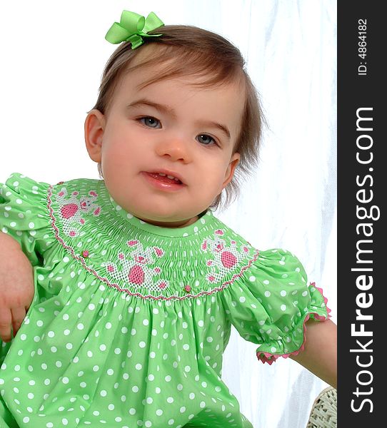 Baby girl in green sitting in front of white background