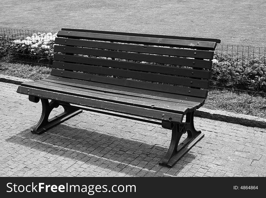 A Bench in a park, flowers behind, black and white