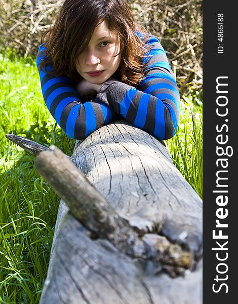Young woman resting on a tree trunk. Young woman resting on a tree trunk.