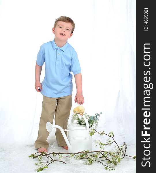 Boy in blue standing with chicken and watering can in front of white background. Boy in blue standing with chicken and watering can in front of white background