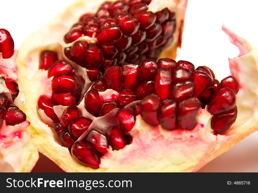 The pomegranate divided into parts on white. The juicy fruit containing set of vitamins, useful to a human body.