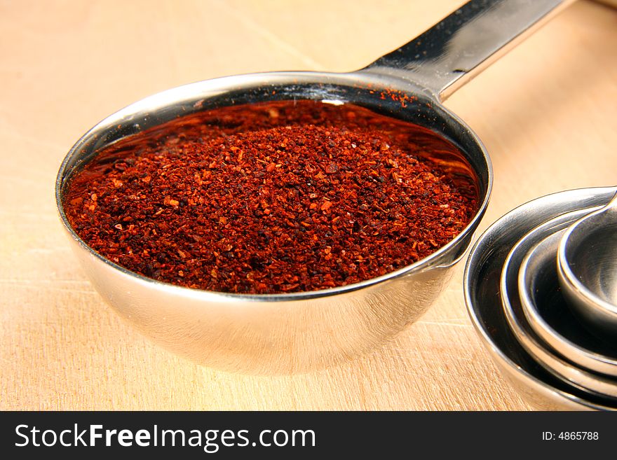 Chili powder in measuring spoon on cutting board. Chili powder in measuring spoon on cutting board