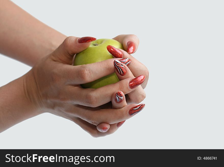 Female hands with manicure on a green apple