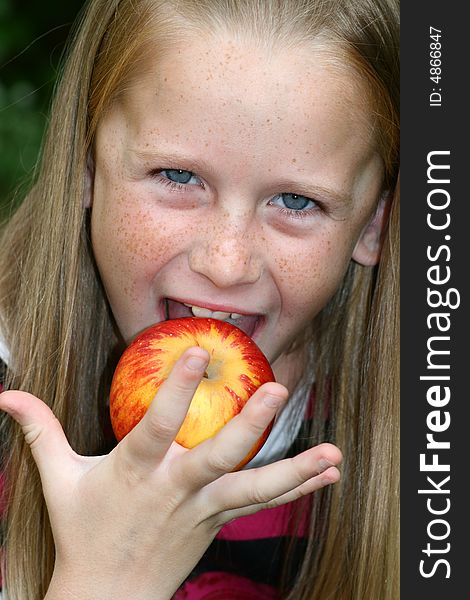 A white caucasian girl child eating an apple. A white caucasian girl child eating an apple