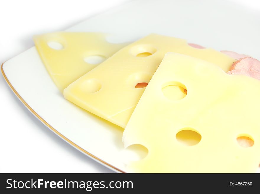 Slices of cheese with holes on plate over white. Slices of cheese with holes on plate over white