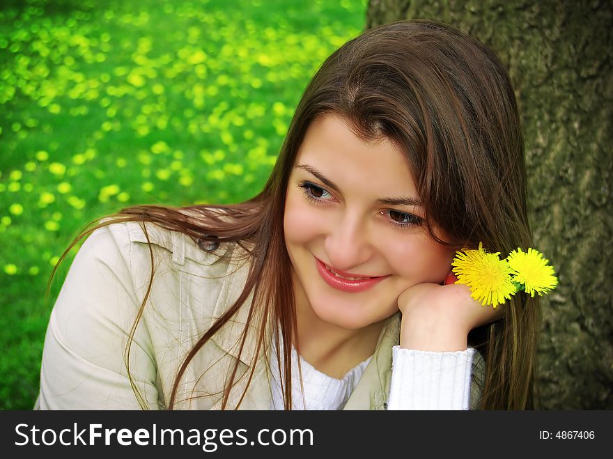 A girl with yellow flowers sitting on the green field