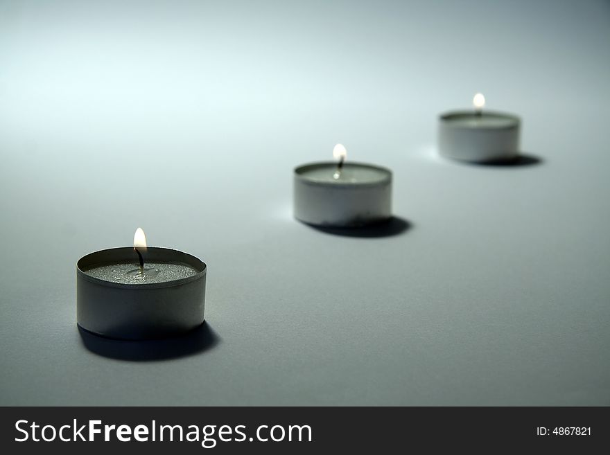 Three small candles on white background, distance blur. Three small candles on white background, distance blur