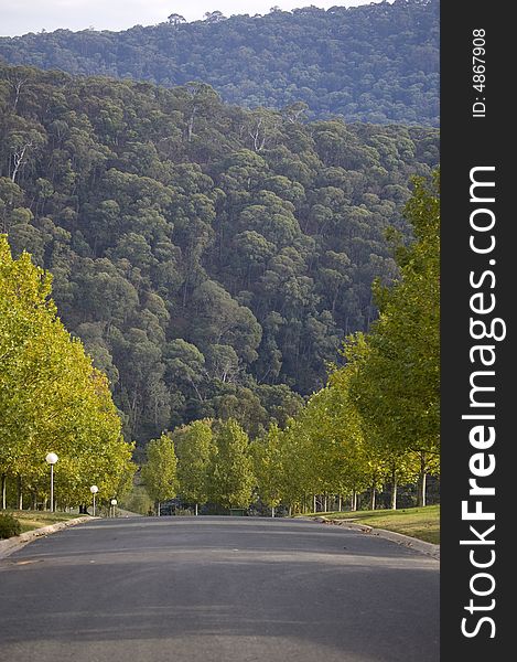 A road disappearing over the hill with wilderness mountains in background. A road disappearing over the hill with wilderness mountains in background