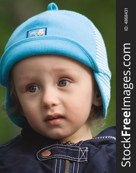 Portrait of the little boy with a blue cap on a dark green background. Portrait of the little boy with a blue cap on a dark green background