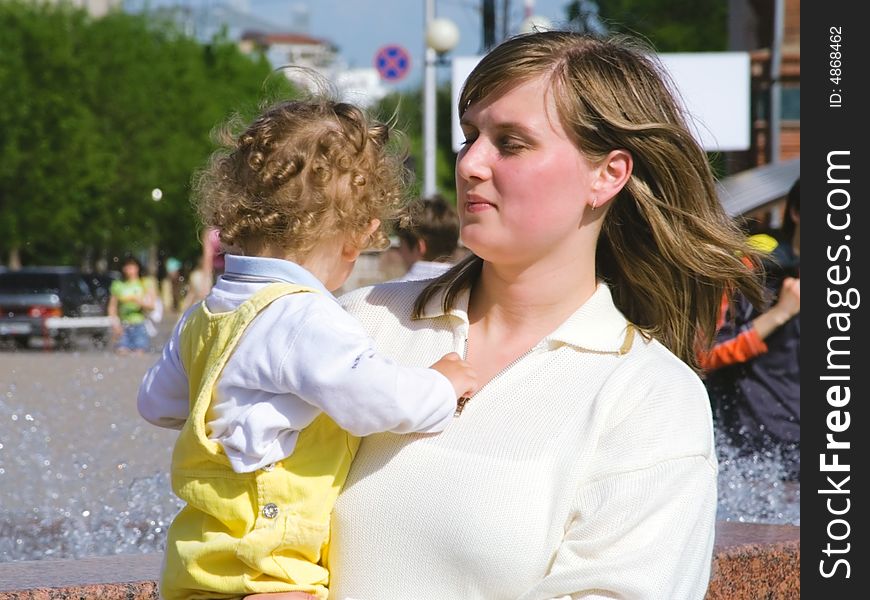 The young woman with the curly boy on hands on a background of the big city. The young woman with the curly boy on hands on a background of the big city