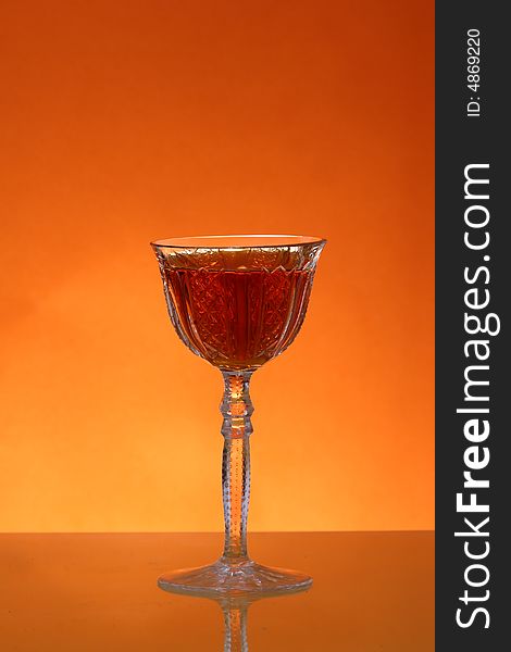 Glass of liqueur over orange background