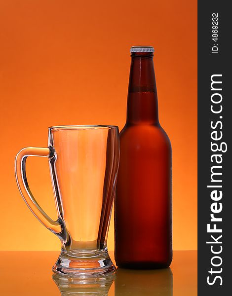 Empty mug and bottle of beer over orange background. Empty mug and bottle of beer over orange background