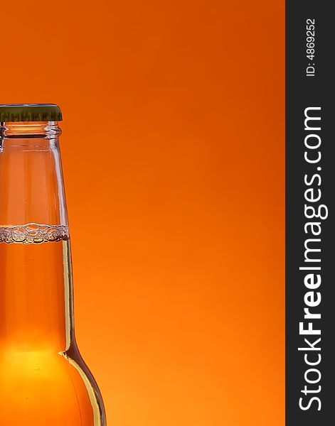 Close up of beer bottle over orange background