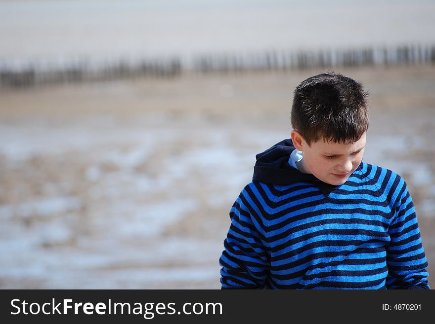 Young boy walking along the deserted beach