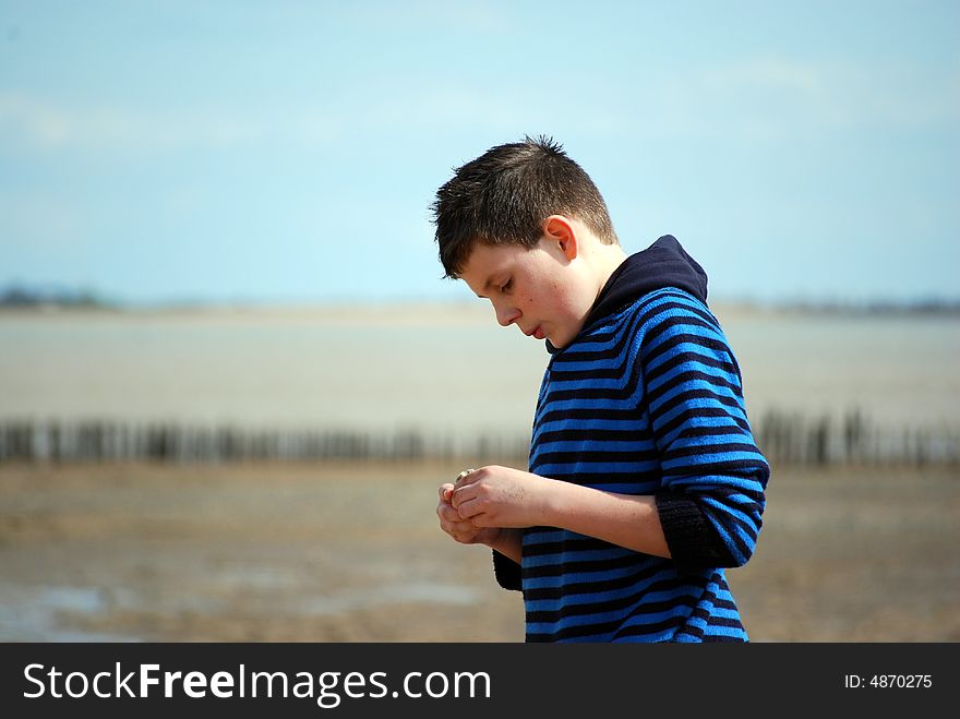 Young boy walking along the deserted beach