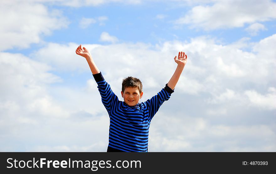 Boy at the seaside with his hands in the air