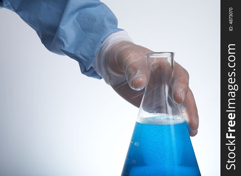 Hand holding erlenmeyer flask with blue liquid