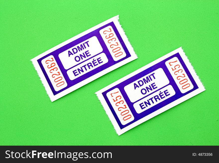 A pair of blue admit one tickets over a green surface