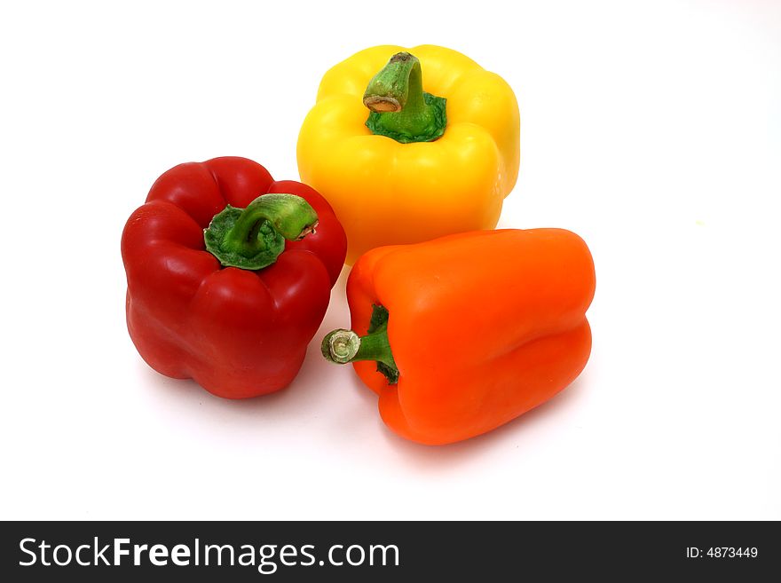 Fresh orange, yellow and red bell peppers over a white surface