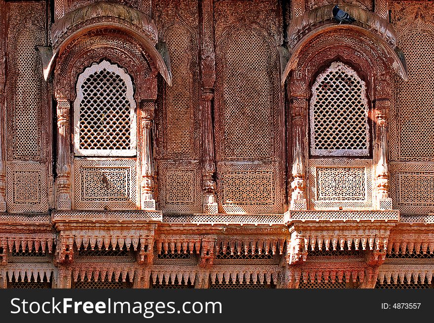 India, Jaisalmer: Indian palace architecture; red walls and wooden carved frame and windows. India, Jaisalmer: Indian palace architecture; red walls and wooden carved frame and windows