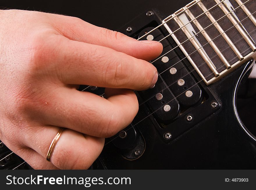 The man plays a close up of a hand on an electroguitar